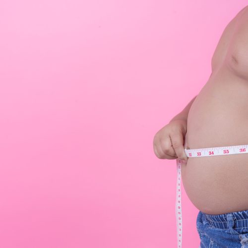 Obese boy who is overweight on a pink background.