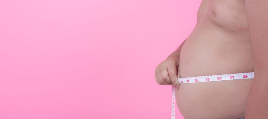 Obese boy who is overweight on a pink background.